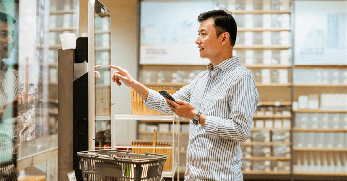 Asian man paying with smartphone at cashier counter.
