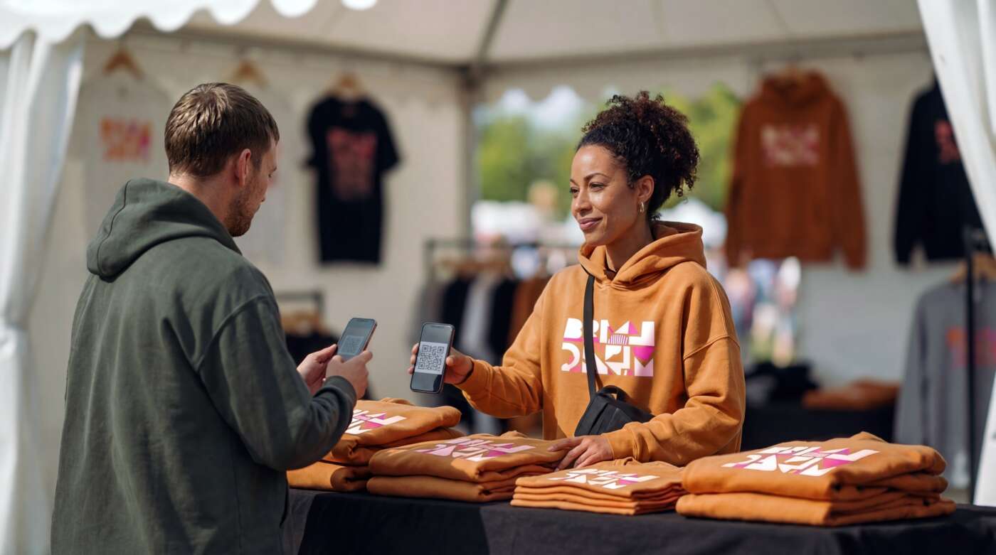 Vendor scanning digital payment from customer at outdoor merchandise stand