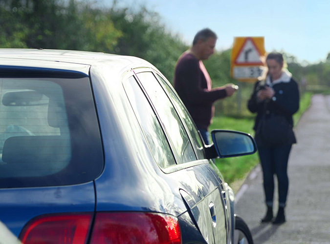 Picture of man and women standing in front of stalled car